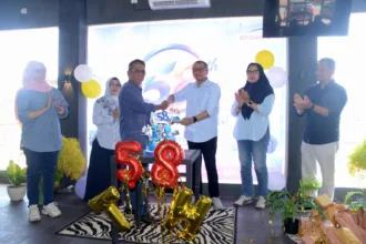 Kepala Diskominfo Cilacap Buddy Haryanto (berkemeja biru) berjabat tangan dengan Direktur Utama LPPL Bercahaya FM Chairil Taufan pada HUT ke-58 Bercahaya FM, Sabtu (19/9/2026).(Foto: Diskominfo Cilacap)