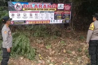 Petugas Polsek Lumbir memasang imbauan berupa spanduk bertuliskan "DILARANG MEMBAKAR HUTAN DAN LAHAN" di kawasan hutan milik Perhutani, Sabtu (12/9/2026).(Foto: Polresta Banyumas)